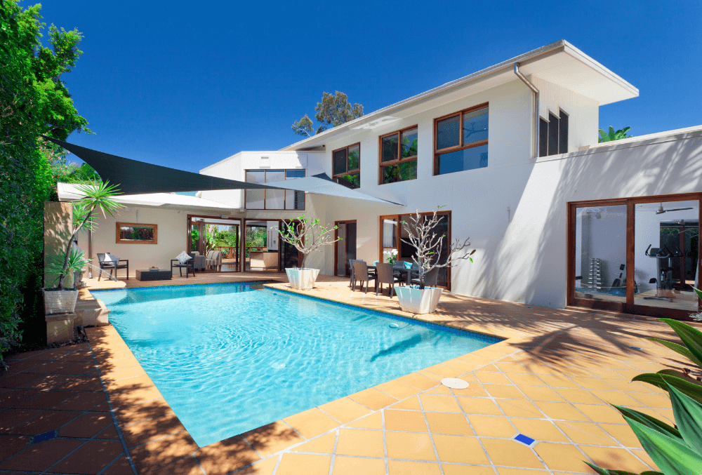 Beautiful modern house with a clear blue swimming pool in the foreground.