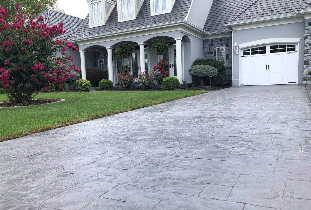 Grey colored stamped concrete driveway in front of a modern house