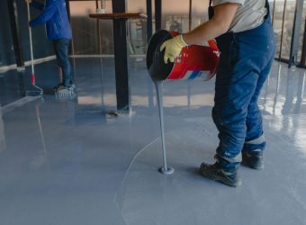 Worker pouring gray epoxy to the new floor