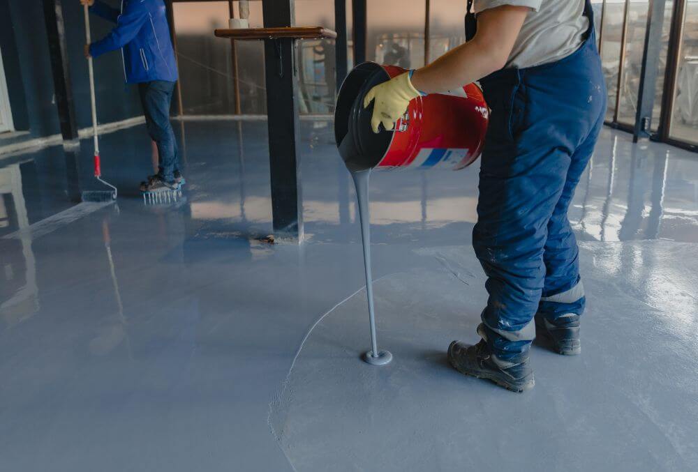 Worker pouring gray epoxy to the new floor
