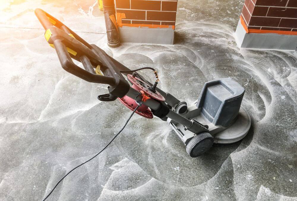 Worker grinding concrete for epoxy installation